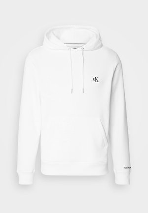 Balta medvilninė hoodie su raišteliu ant galvos, priekinė kišenė ir juodas išsiuvinėtas cK logotipas ant krūtinės. Ribiuoti rankogaliai ir apykaklė.