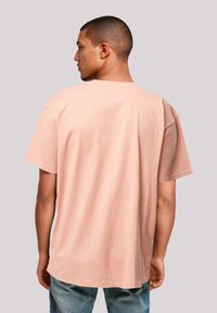 Rosa Baumwoll-T-Shirt mit kurzen Ärmeln, lockerer Passform und Rundhalsausschnitt, von hinten gezeigt. Weiche Textur ohne Verzierungen.