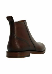 Bottines Chelsea en cuir marron avec une tige lisse, un talon texturé et une languette à l'arrière. Semelle plate avec un talon modeste.