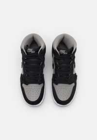 Paire de baskets montantes Nike Air noires et grises avec des lacets noirs, vues de dessus sur fond blanc.