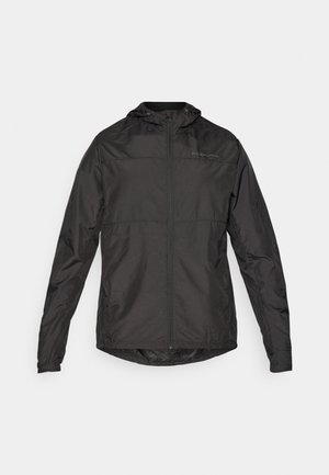 Veste noire imperméable légère avec capuche, fermeture éclair avant, poignets élastiques et logo discret sur la poitrine. Texture lisse.