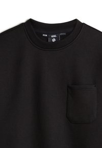 Sweatshirt noir en coton épais, avec un col rond, un col côtelé et une poche poitrine de forme rectangulaire.