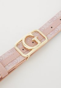 Roze leren riem met een textuur overlay. Voorzien van een grote gouden rechte gesp met de letter "G" prominent weergegeven.