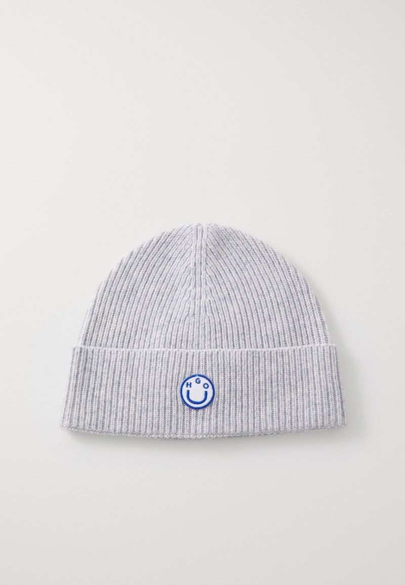 Grijze ribbelgebreide beanie met een omgeslagen rand, voorzien van een blauw geborduurd glimlachend gezicht en de tekst "HGO." Zachte textuur.