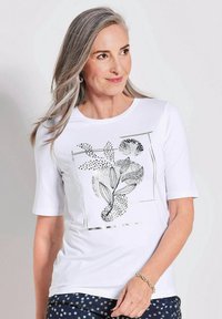 Weißes T-Shirt mit kurzen Ärmeln, das ein schwarzes und silbernes abstraktes botanisches Muster zeigt. Weicher Stoff mit Rundhalsausschnitt und lockerer Passform.