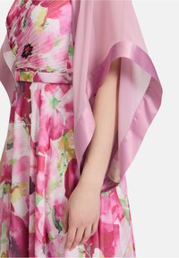 De bloemenjurk heeft een mix van roze en groene aquarelpatronen, gecombineerd met een sheer, lichtroze sjaal met satijnen randen.