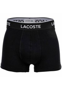 Svarta bomullsboxershorts med ett tjockt elastiskt midjeband som har "LACOSTE"-logotypen i vitt. Slät textur och åtsittande design.