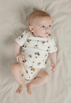 Korte mouwen babyslijper in crème met bruine dierenprints, waaronder leeuwen en olifanten, met ronde hals en drukknoopsluiting aan de onderkant.