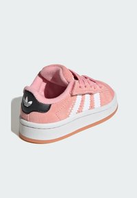 Ružové semišové tenisky Adidas Campus s bielymi pruhmi, čiernym pätkovým panelom, ružovými šnúrkami a bielou podrážkou s gumovou spodnou časťou, zobrazené z uhlu zozadu.