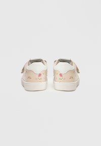 Ζεύγος ανοιχτόροζ παπουτσάκια για νήπια με λευκές σόλες και μικρά λουλουδάτα σχέδια, που φαίνονται από πίσω σε λευκό απλό φόντο.