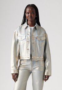 Metallisk silverfärgad kort denimjacka med klassisk krage, två bröstfickor och knäppning fram, kombinerad med matchande byxor.