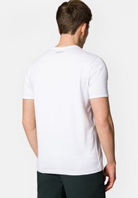 Biała koszulka z krótkim rękawem, z okrągłym dekoltem, wykonana z miękkiego materiału, z subtelnym logo z tyłu i dopasowanym krojem.