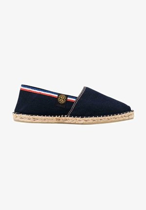 Espadrille en toile marine avec semelle en jute tressé, présentant un accent rayé rouge et blanc et un patch de logo de marque noir sur le côté.