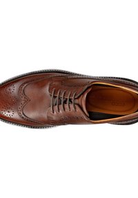 Ruskeat nahkasandaalit, joissa on brogue-yksityiskohtia, pyöreä kärki ja klassinen nauhakiristys. Ominaisuuksina ovat sileä pinta ja hienovarainen kiilto.