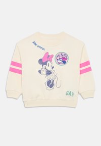 Kremgenser med rosa striper på ermene. Har et Minnie Mouse-mønster og teksten "BON-JUITFUL" over. Laget av mykt materiale.