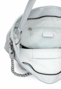 Valkoinen nahkalaukku, jossa on pehmeä pinta, sisäinen vetoketjutasku, hopeiset metalliosat ja punottu olkahihna.