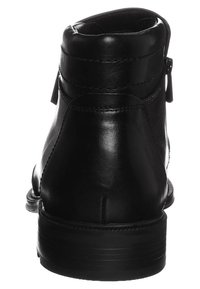 Bottine en cuir noir à finition lisse, bout rond, talon surélevé, fermeture éclair latérale et détails de couture discrets. La semelle présente des rainures horizontales.