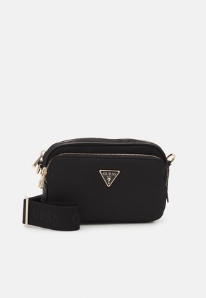 Sacola crossbody preta de nylon com um logótipo triangular dourado, fecho com zíper e uma alça larga ajustável com a palavra "GUESS" em preto.