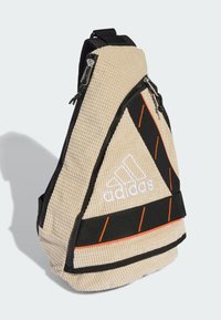 Bežinės tekstūros šoninė rankinė su juodais akcentais, oranžinėmis juostelėmis ir baltu "Adidas" logotipu. Yra užtrauktuku uždaromas skyrius ir reguliuojama juosta.