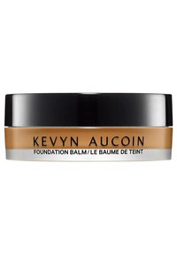Kevyn Aucoin foundation balm in a round, black and clear container. Creamy texture; golden-brown color; text on the label in black.