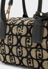 Borsa a tracolla beige e nera con motivo, manici in pelle nera e logo "LIU JO" in oro con dettagli hardware.