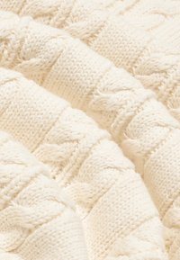 Țesătură tricotată de culoare crem, cu un model texturat în ribi, având secțiuni rasucite proeminente și un aspect moale și confortabil.
