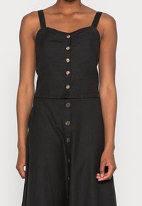 Crop top en lin noir avec décolleté carré, bretelles ajustables et fermeture à boutons à l'avant. Texture lisse avec une coupe ajustée et un léger éclat.