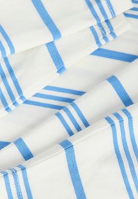 Λευκό ύφασμα με διπλωμένες άκρες, με ομοιόμορφα κατανεμημένες κάθετες και οριζόντιες ανοικτό μπλε ραβδώσεις που σχηματίζουν μοτίβο πλέγματος.