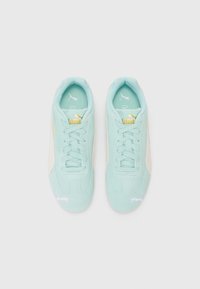 Baskets Puma basses bleu clair avec rayures blanches sur les côtés, accents en or et blanc du logo Puma, et lacets, vues du dessus sur fond blanc.