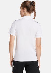 Witte polo shirt met korte mouwen, voorzien van een kraag, textuurstof en zwarte accenten op de schouders.