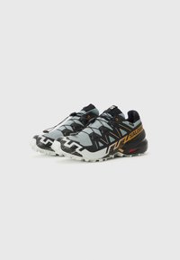 Chaussures de trail running avec un dessus bleu clair, des accents noirs, une semelle en caoutchouc texturée et un motif géométrique distinctif sur les côtés.