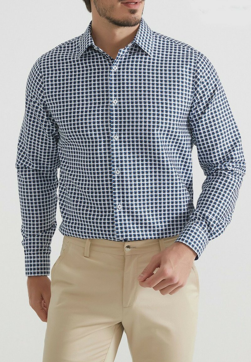 Chemise à manches longues boutonnée en blanc avec un motif à carreaux bleus. Dotée d'un col standard et d'une texture de tissu lisse.