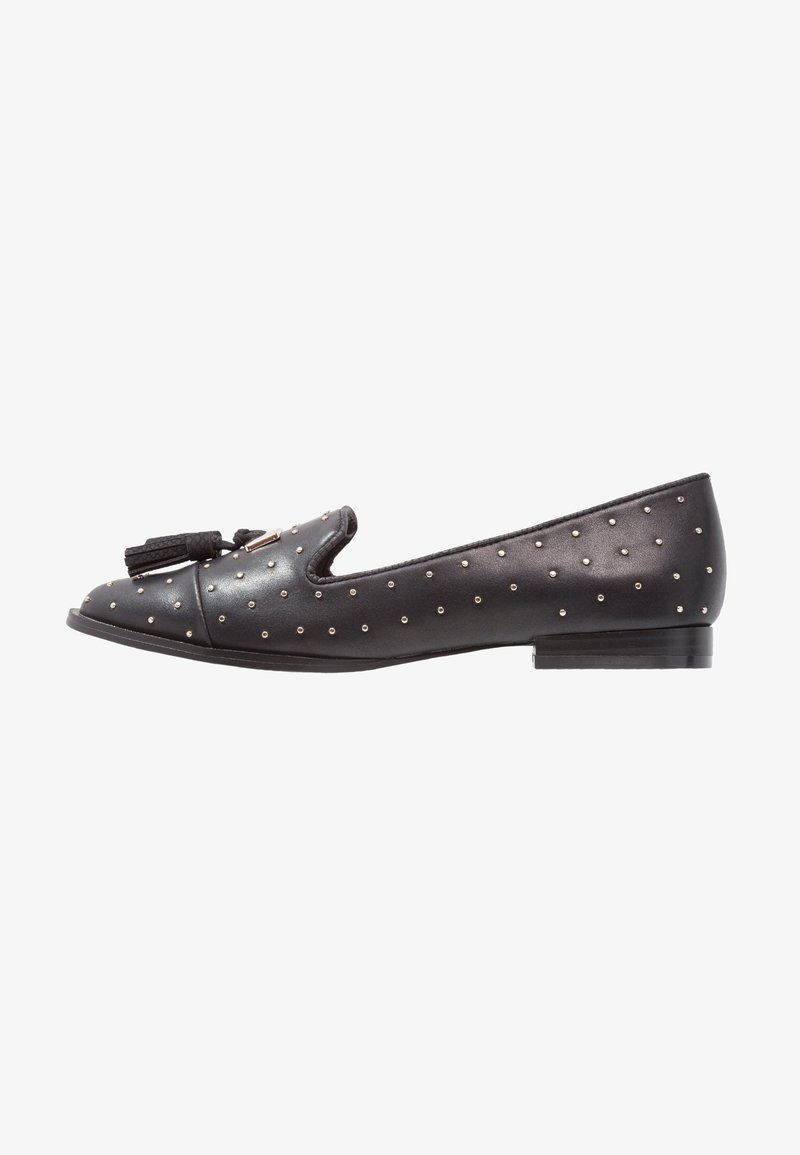 Mocassin plat en cuir noir avec clous argentés, détail de gland tressé à l'avant et petit talon.
