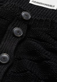 Schwarze Strickjacke mit strukturiertem Muster, fünf grauen Knöpfen und einem Etikett mit der Aufschrift "ARMEDANGELS." Weicher Stoff mit einem gemütlichen Aussehen.
