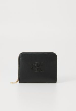 Black leather wallet with embossed "cK" logo, zip closure, and gold hardware accents. Smooth texture with a rectangular shape.