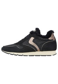 Černý sportovní sneaker s texturovaným svrškem, semišovými akcenty a bronzovým kovovým detailem. Má nadýchaný límec a bílou podrážku.