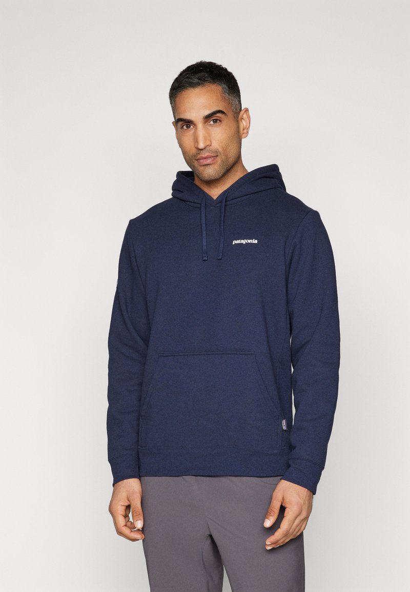 Sweatshirt à capuche bleu marine en tissu doux, avec une poche frontale et un petit logo Patagonia blanc sur la poitrine.