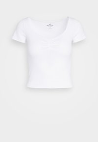 Bílý krátký rukávový croptop vyrobený z žebrované látky. Má výstřih do V se sklady uprostřed. Jednoduchý design.