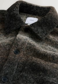 Kurtka z wełny w odcieniach brązu i szarości, z kołnierzykiem, zapinana na guziki, wykonana z miękkiego, teksturowanego materiału o lekko puszystej powierzchni.