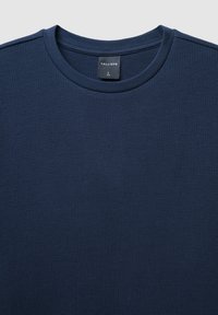 T-shirt blu navy con texture e scollatura rotonda, caratterizzato da un design a maglia waffle. Etichetta del marchio "CALLIOPE" visibile all'interno del collo. Taglia L.