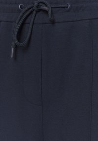Navy blue joggers made of soft, textured fabric with an elastic waistband and drawstring, featuring a side pocket for convenience.