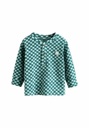 Blusa de manga larga a cuadros verdes y blancos con cuello henley, tres botones de madera y un pequeño parche con logo en la parte frontal.
