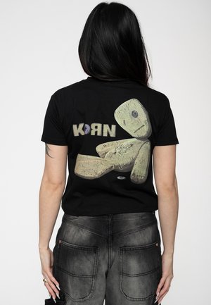 Black cotton t-shirt featuring a graphic design of a doll and the word "KORN" in colorful letters on the back. Short sleeves, fitted cut.
