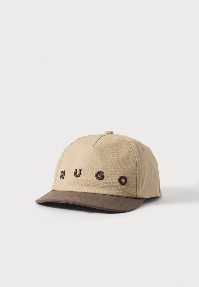 Casquette de baseball beige et marron avec « HUGO » brodé en lettres marron à l'avant, présentée sur un fond blanc uni.