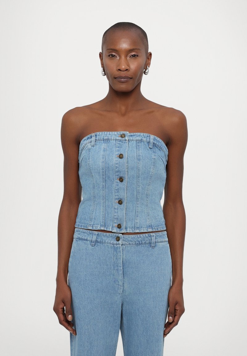 Denim strapless topp i lyseblå har knappelukking, skreddersydd passform og sømdetaljer. Glatt tekstur uten ytterligere mønstre.