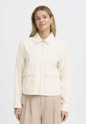 Világos krémszínű dzseki függőleges csíkokkal, cipzáras záródással, hegyes gallérral és két elülső zsebbel. Puha textúrájú és kényelmes, laza szabású kialakítás.