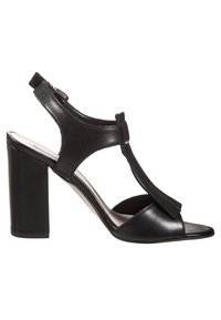 Černé sandály na podpatku vyrobené z hladké kůže, s otevřenou špičkou, designem T-strap a robustním blokovým podpatkem. Obsahují detail s třásněmi na přední části.