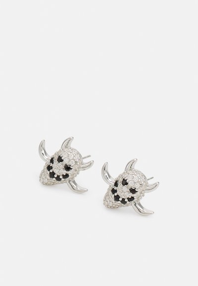 Silver skull-shaped earrings adorned with black accents and clear gems. They feature horn-like protrusions and a textured surface.