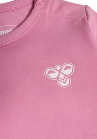 Roze katoenen rompertje met een ronde halslijn, voorzien van een witte bijafbeelding op de voorkant. Drukknoopsluiting op de schouder voor gemakkelijk aan- en uittrekken.