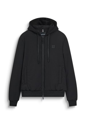Black quilted zip-up hoodie with front pockets, drawstring hood, ribbed cuffs, and waistband, featuring a small logo patch on the chest.